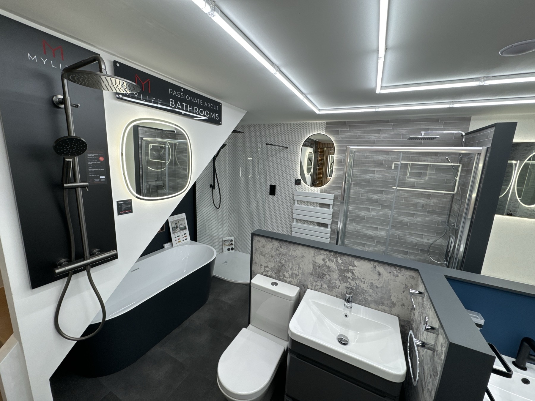 A wider view of the showroom floor — multiple bathroom and vanity displays laid out to compare finishes, tapware and tiling side by side.